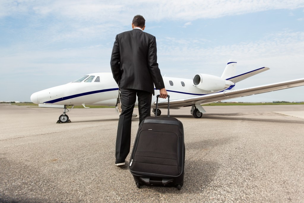 Rear view of businessman with luggage walking towards corporate jet